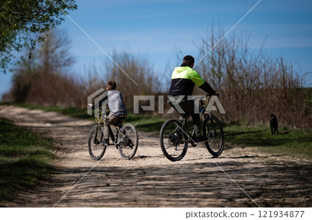 Father and son enjoy a sunny bike ride along a country path. Father and son enjoy a sunny bike ride along a country path. 121934877
