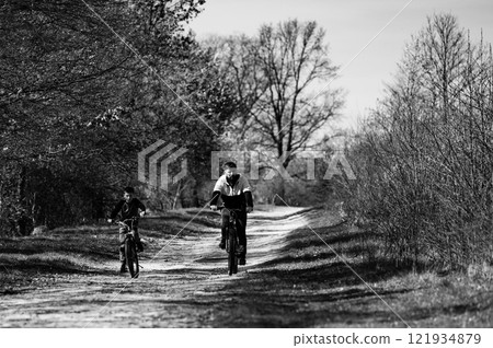 Father and son cycling on a country path, enjoying a sunny day outdoors. Father and son cycling on a country path, enjoying a sunny day outdoors. 121934879