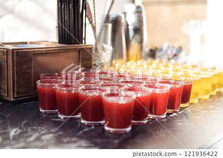Smooth rows of glasses with delicious refreshing berry and fruit drinks. Fresh fragrant cocktails on the bar counter. Orange and raspberry juice on a buffet. Smooth rows of glasses with delicious refreshing berry and fruit drinks. Fresh fragrant cocktails on the bar counter. Orange and raspberry juice on a buffet. 121936422