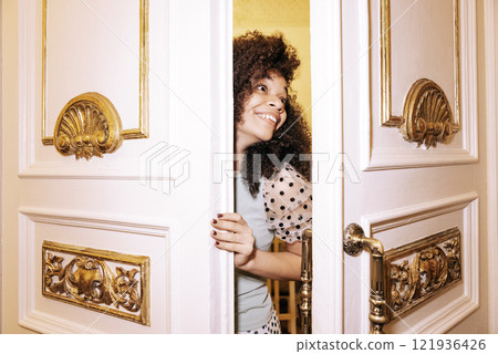 Young African in white elegant dress looks out from behind door. Young African in white elegant dress looks out from behind door. 121936426