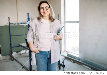 Young attractive woman in glasses and casual clothes checks repair. Young attractive woman in glasses and casual clothes checks repair. 121936447