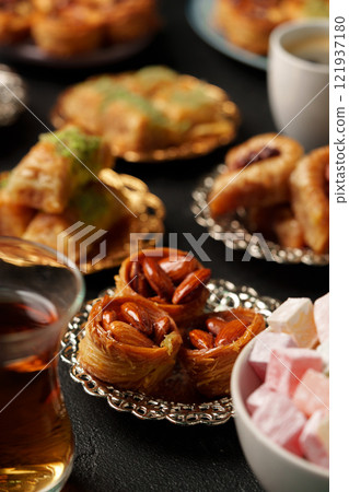 Delicious assortment of traditional sweets and pastries served with tea at a cozy gathering Delicious assortment of traditional sweets and pastries served with tea at a cozy gathering 121937180