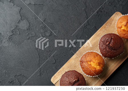Muffins displayed on wooden board with dark textured background in a culinary setting 121937230