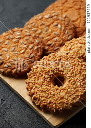 Delicious assortment of homemade cookies with nuts and seeds on wooden platter 121937239