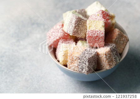 Colorful dessert cubes arranged in a bowl on a light surface ready for enjoyment 121937258
