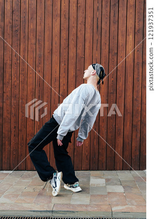 A man wearing a bandana dances in front of a brown wooden wall A man wearing a bandana dances in front of a brown wooden wall 121937351