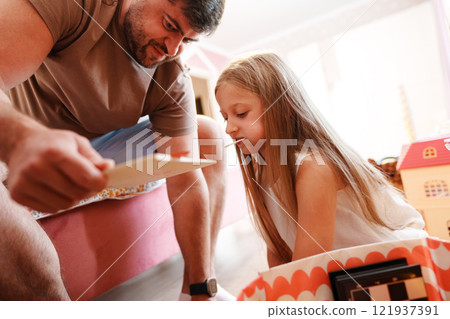 A father and daughter play a game in their home, engrossed in the activity A father and daughter play a game in their home, engrossed in the activity 121937391
