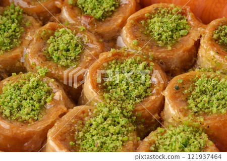 Delicious traditional dessert with pistachio topping served in a vibrant wooden dish 121937464