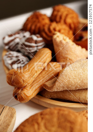 Assorted traditional pastries displayed on a wooden plate during a festive gathering 121937574