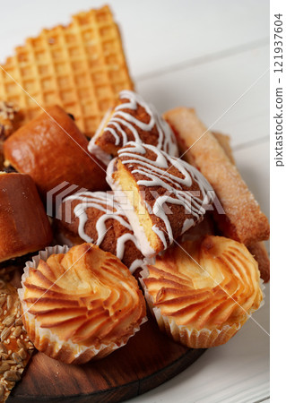 Assorted pastries and sweets arranged on a wooden platter during a food gathering 121937604