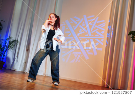 A young woman in jeans and a white shirt dances on a stage with a blue light shining on her A young woman in jeans and a white shirt dances on a stage with a blue light shining on her 121937807