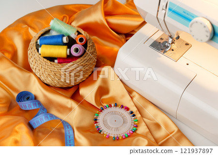 Sewing machine in use on a wooden table, stitching a light fabric in a well-lit indoor workspace 121937897