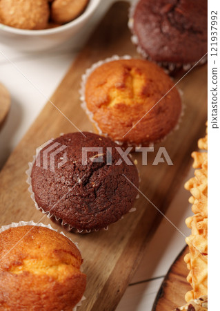 Freshly baked muffins displayed on a wooden board with assorted snacks for a cozy afternoon treat 121937992