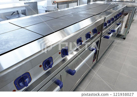 Stainless steel commercial griddles arranged in a modern kitchen with ample workspace for food preparation Stainless steel commercial griddles arranged in a modern kitchen with ample workspace for food preparation 121938027