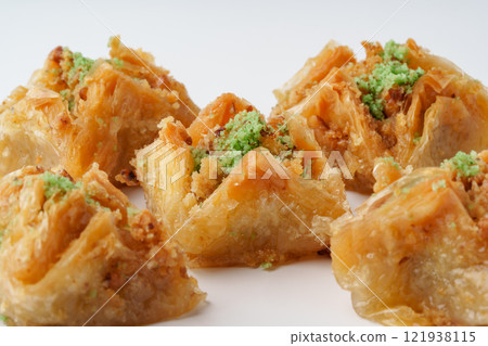 Deliciously crafted baklava pieces decorated with green pistachio topping and arranged on a white surface Deliciously crafted baklava pieces decorated with green pistachio topping and arranged on a white surface 121938115