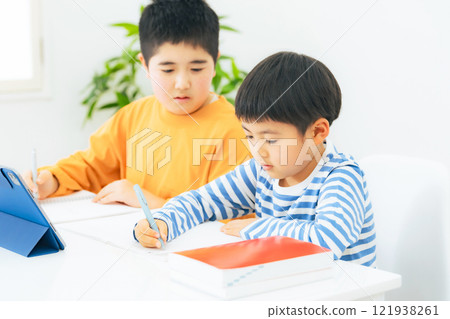 Elementary school siblings taking online classes on tablets 121938261