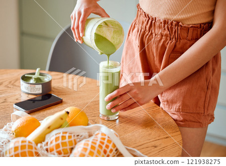 Closeup of a female pouring green healthy smoothie to detox, drinking vitamins and nutrients. Woman nutritionist having a fresh fruit juice to cleanse and provide energy for healthy lifestyle Closeup of a female pouring green healthy smoothie to detox, drinking vitamins and nutrients. Woman nutritionist having a fresh fruit juice to cleanse and provide energy for healthy lifestyle 121938275