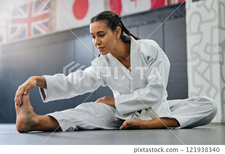 Exercise, fight and workout stretch of a karate school student with focus before training start. Sport woman or coach stretching for an exercise at a dojo studio, performance gym or martial arts club Exercise, fight and workout stretch of a karate school student with focus before training start. Sport woman or coach stretching for an exercise at a dojo studio, performance gym or martial arts club 121938340