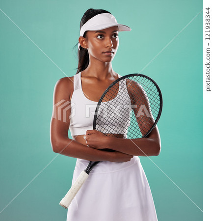 Thinking tennis player, fitness athlete and active woman ready for training with racket in cool fashion and sports uniform while posing on green studio background. Healthy and serious young female 121938344