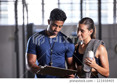 Coach planning workout, schedule and training with athlete for active, fitness and wellness in a gym. Trainer writing notes for sports client with routine to gain toned, strong and fit body muscle Coach planning workout, schedule and training with athlete for active, fitness and wellness in a gym. Trainer writing notes for sports client with routine to gain toned, strong and fit body muscle 121938405
