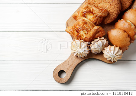 Assorted baked goods arranged on a wooden serving board in a light-filled kitchen Assorted baked goods arranged on a wooden serving board in a light-filled kitchen 121938412