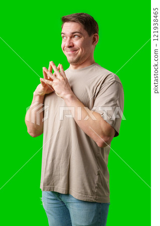 A man smiles thoughtfully while standing against a bright green background 121938465