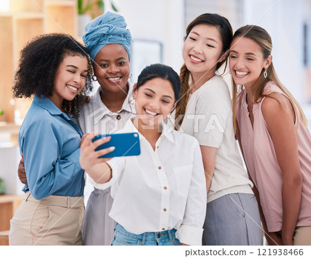 Diverse fun business friends taking selfies on a phone together in an office. Happy and beautiful colleagues or friends smiling for photos and posing as an ambitious team in a startup agency Diverse fun business friends taking selfies on a phone together in an office. Happy and beautiful colleagues or friends smiling for photos and posing as an ambitious team in a startup agency 121938466