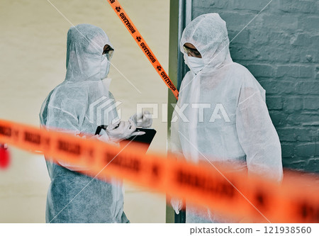 Forensic investigators collecting evidence at a murder scene in a building with barrier tape. Criminal researchers investigating a crime site and talking about the incident or case 121938560