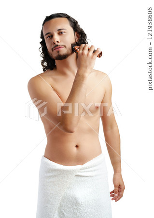 A young man with curly hair grooming his beard using an electric trimmer 121938606