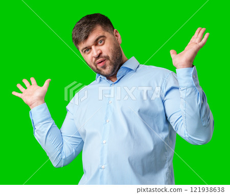 A man playfully posing with a quirky expression against a bright green background 121938638