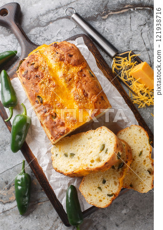 Fresh baked sliced bread loaf with Cheese and Jalapeno closeup on the wooden board on the table. Vertical top view Fresh baked sliced bread loaf with Cheese and Jalapeno closeup on the wooden board on the table. Vertical top view 121938716