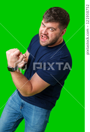 A strong man with fists raised, smiling confidently, on a bright green background 121938752