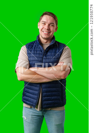 Confident man in a navy vest and t-shirt poses with crossed arms against a bright green background Confident man in a navy vest and t-shirt poses with crossed arms against a bright green background 121938774