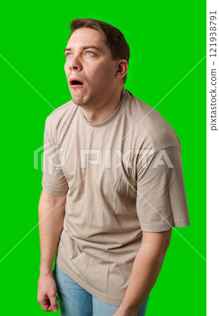 Man making a humorous expression against a bright green background 121938791