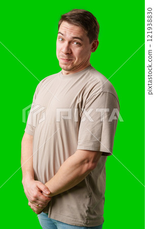 A man smiles thoughtfully while standing against a bright green background 121938830