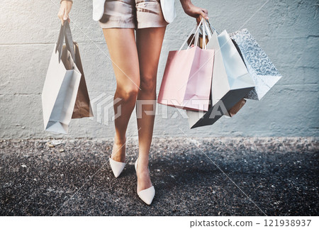 Shopping, spending and fashion with a woman carrying bags, looking for a sale or bargain and enjoying retail therapy. Closeup of a trendy, stylish and fashionable female consumer with giftbags Shopping, spending and fashion with a woman carrying bags, looking for a sale or bargain and enjoying retail therapy. Closeup of a trendy, stylish and fashionable female consumer with giftbags 121938937