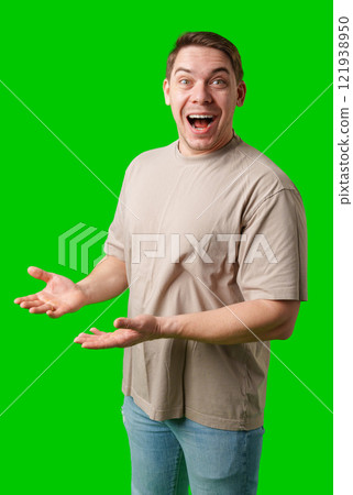 Young man in casual clothing stands with open arms against a vibrant green background 121938950