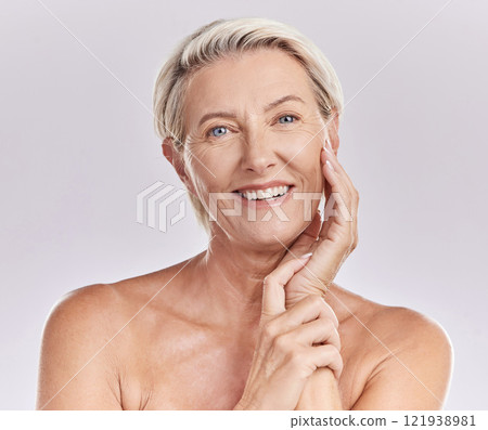 Portrait of happy smiling mature caucasian woman looking positive and cheerful against studio background. Smooth face and skin of an older female or antiaging beauty model doing her skincare routine 121938981