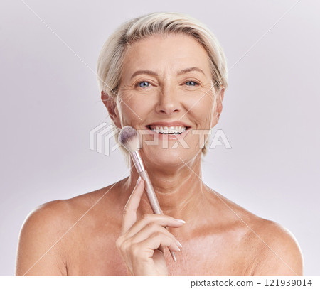 Beauty, skincare and makeup with a senior woman applying cosmetics to her face in studio against a purple background. Head portrait of a female with blusher looking beautiful, happy and healthy 121939014