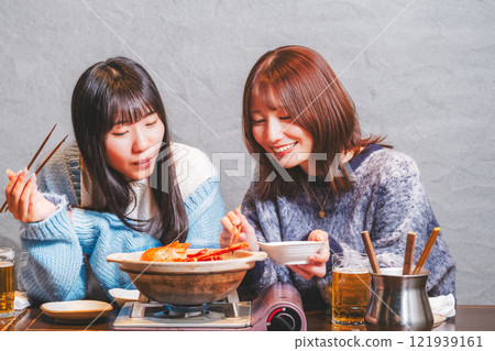Young women having a girls' night out with crab hotpot [Photo courtesy of Seafood Izakaya Gyoruko] 121939161