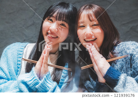 Two young women saying "Itadakimasu" in front of a crab hotpot [Photo courtesy of Seafood Izakaya Gyoruko] 121939176