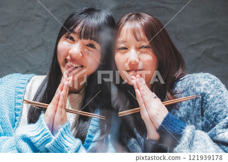 Two young women saying "Itadakimasu" in front of a crab hotpot [Photo courtesy of Seafood Izakaya Gyoruko] 121939178