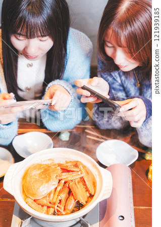 兩位年輕女子用智慧型手機拍攝令人驚豔的螃蟹火鍋[攝影合作：海鮮居酒屋Uoroko] 121939185