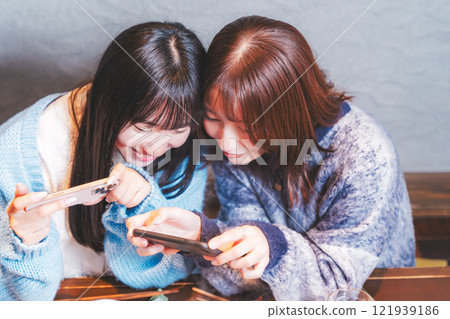 兩位年輕女子用智慧型手機拍攝令人驚豔的螃蟹火鍋[攝影合作：海鮮居酒屋Uoroko] 121939186