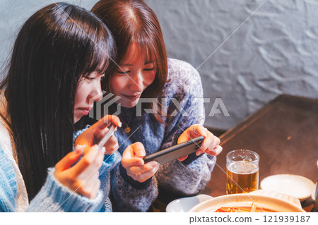 兩位年輕女子用智慧型手機拍攝令人驚豔的螃蟹火鍋[攝影合作：海鮮居酒屋Uoroko] 121939187