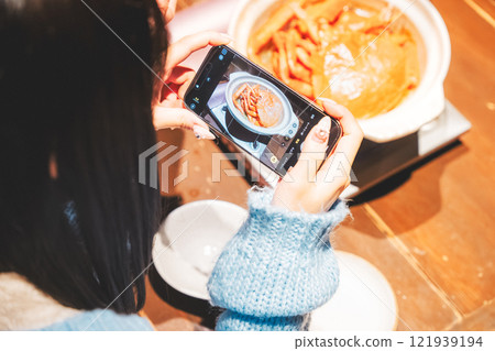 Two young women taking pictures of the beautiful crab hotpot with their smartphones [Photo courtesy of Seafood Izakaya Gyoruko] 121939194