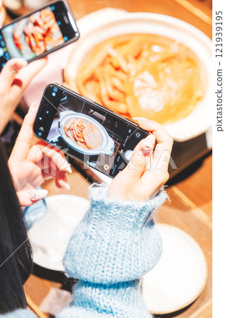 Two young women taking pictures of the beautiful crab hotpot with their smartphones [Photo courtesy of Seafood Izakaya Gyoruko] 121939195