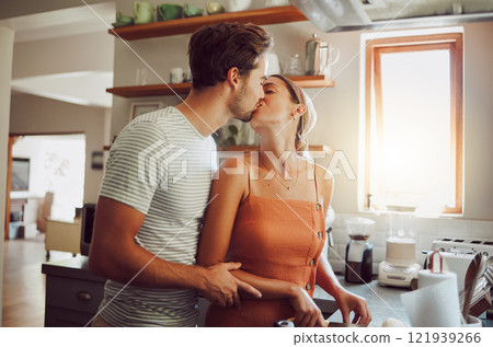 Romantic couple kissing, cooking and showing affection in love while bonding together in a kitchen at home. Caring boyfriend and girlfriend in a loving relationship sharing an intimate special moment 121939266