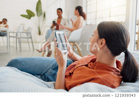 Creative businesswoman, designer or digital marketing agency employee on her phone browsing and searching on a break. Female worker reading or looking for ideas for social media trends on bean bag. Creative businesswoman, designer or digital marketing agency employee on her phone browsing and searching on a break. Female worker reading or looking for ideas for social media trends on bean bag. 121939343