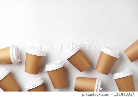 A variety of disposable coffee cups arranged artistically on a clean white surface 121939384